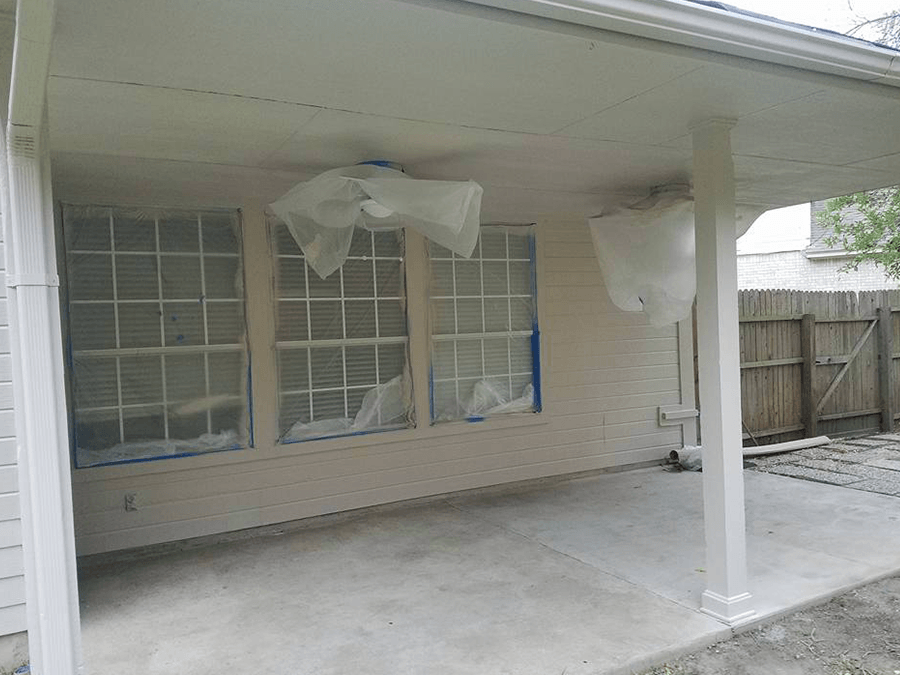 A white house with a ceiling fan and a covered patio.