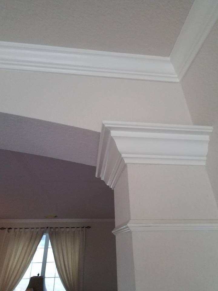 A living room with white walls and a white molding on the ceiling.