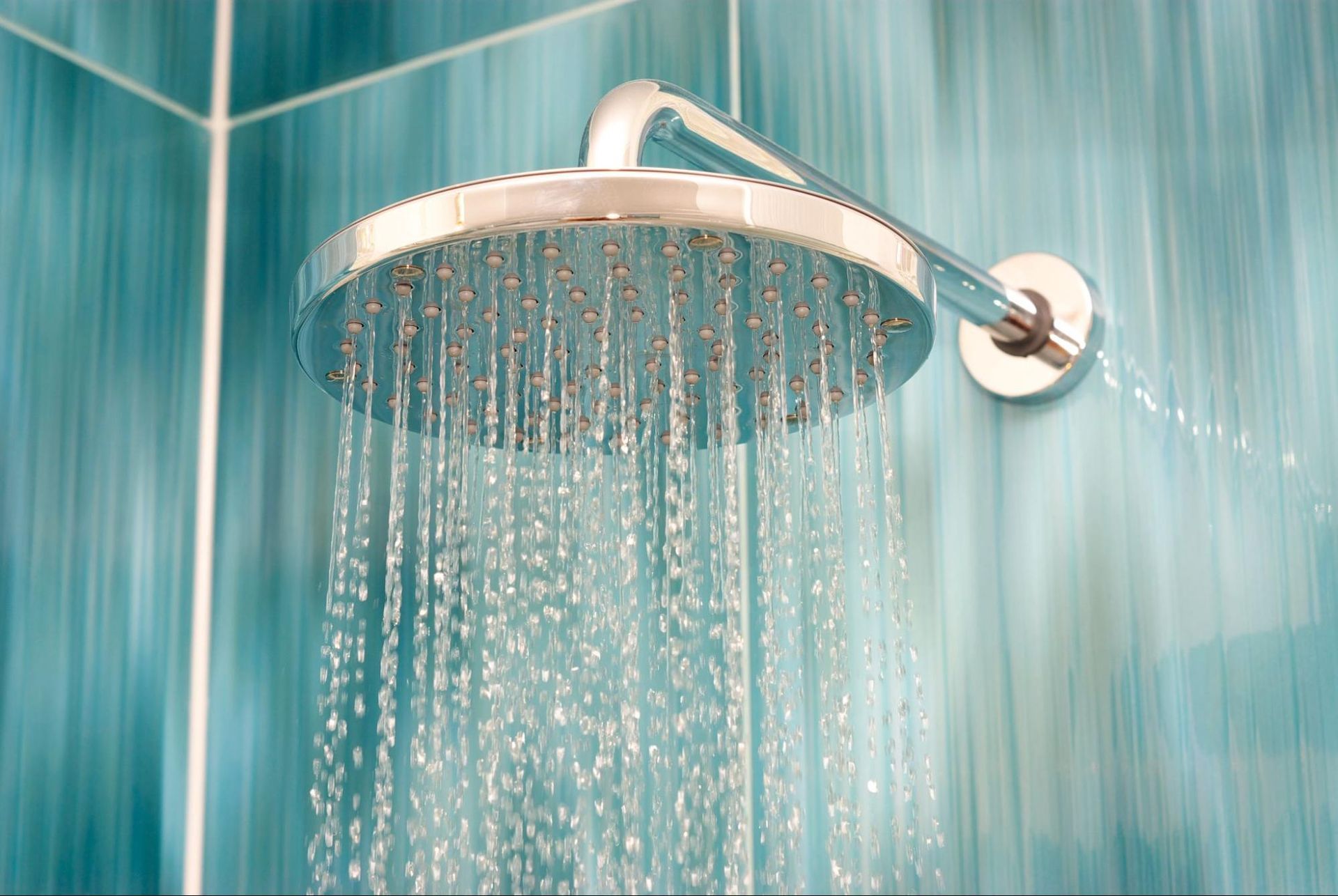 A close up of a shower head with water coming out of it in a bathroom.