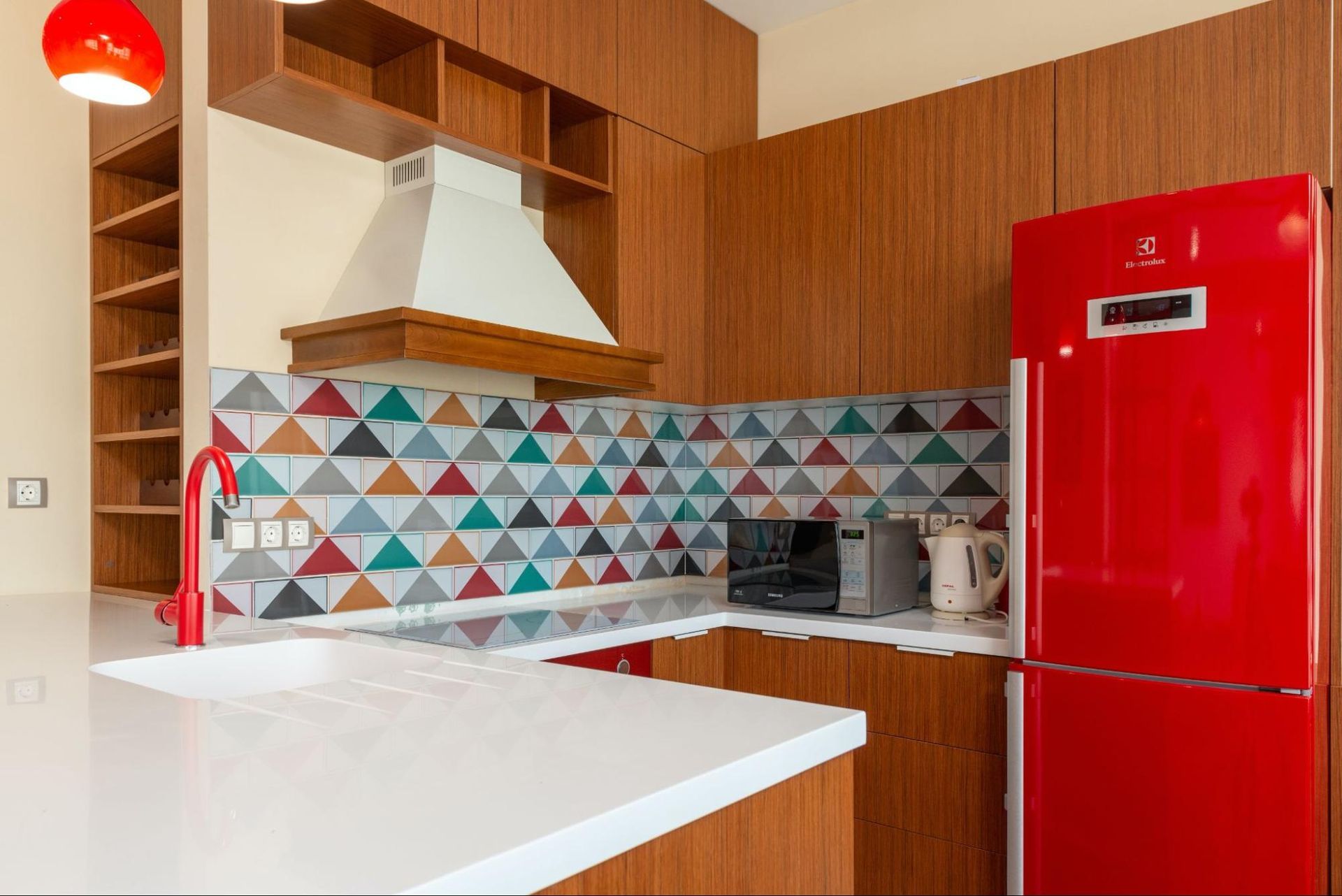 A kitchen with a red refrigerator and a red sink.