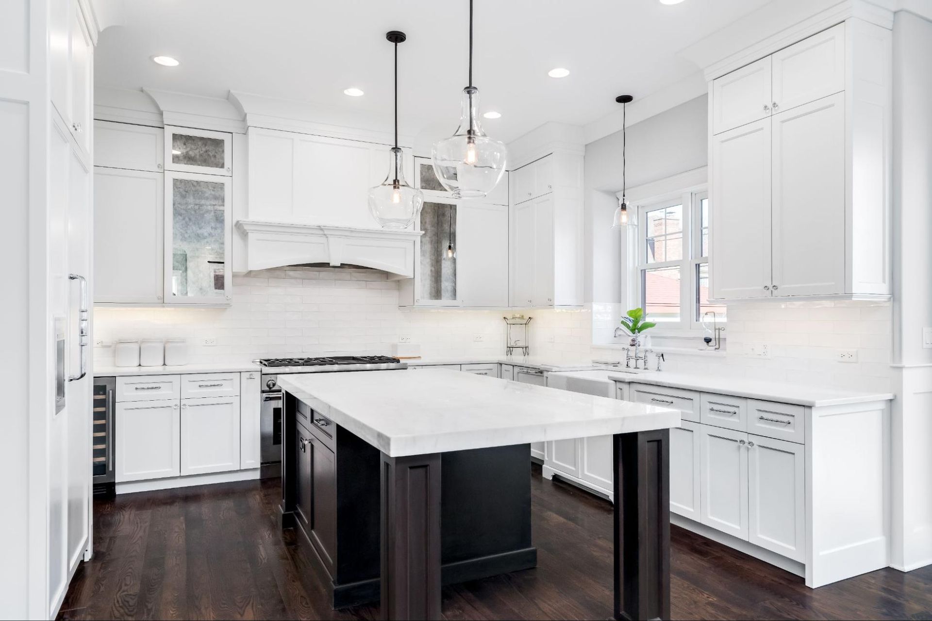 A kitchen with white cabinets and a black island.