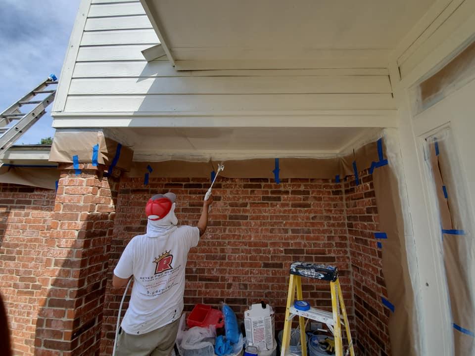 A man is painting a brick building with a brush.