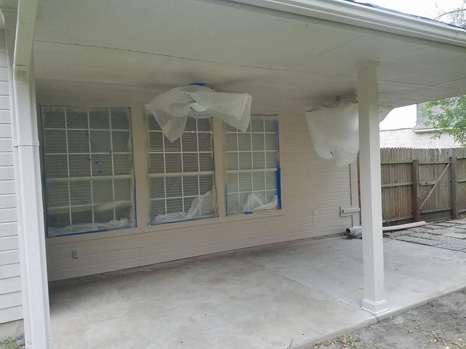 A white house with a porch and windows covered in plastic.
