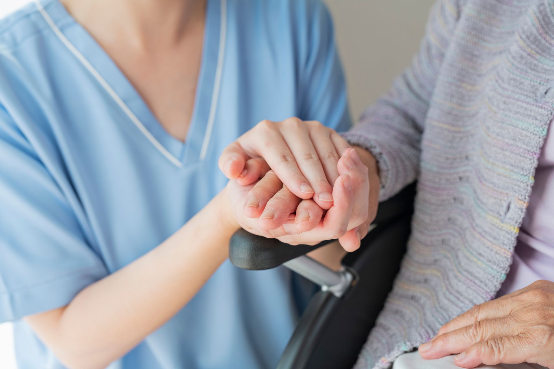 non medical care in matthews nc Nurse holding the hand of an elderly person in a wheelchair, offering comfort and support.