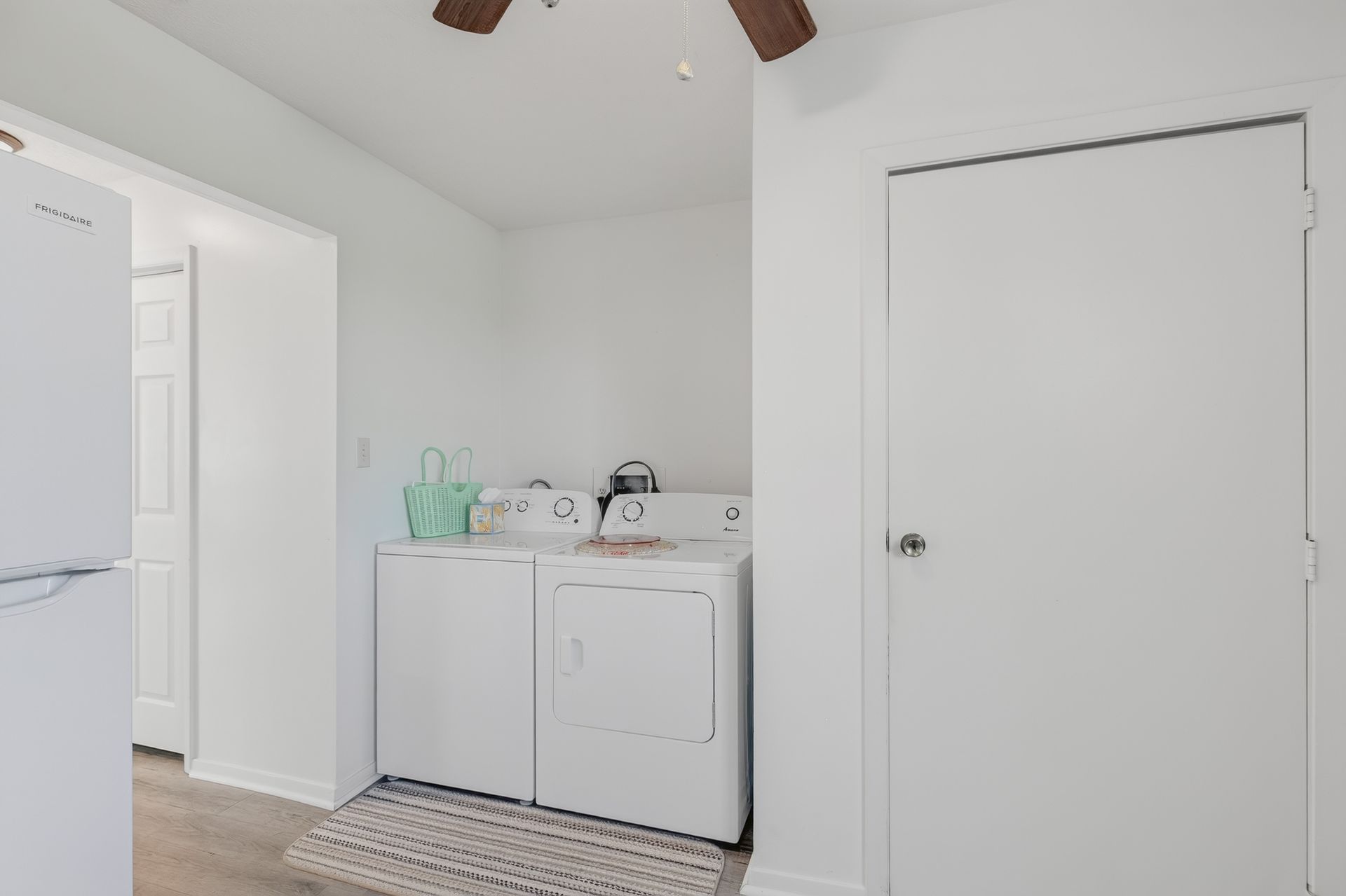 Laundry room with white washer and dryer, sink cabinet, and a closed door on patterned tile floor.