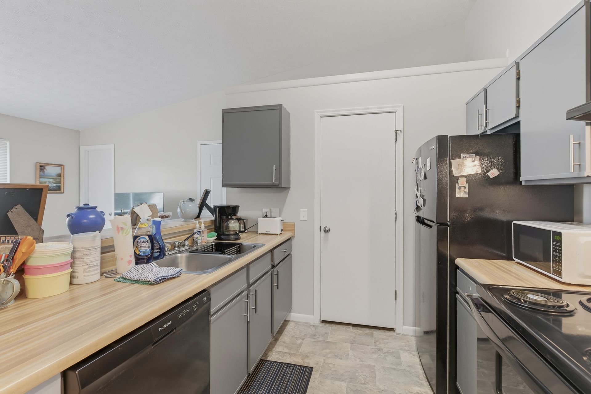 Modern kitchen with gray cabinets, black appliances, and light wood countertops