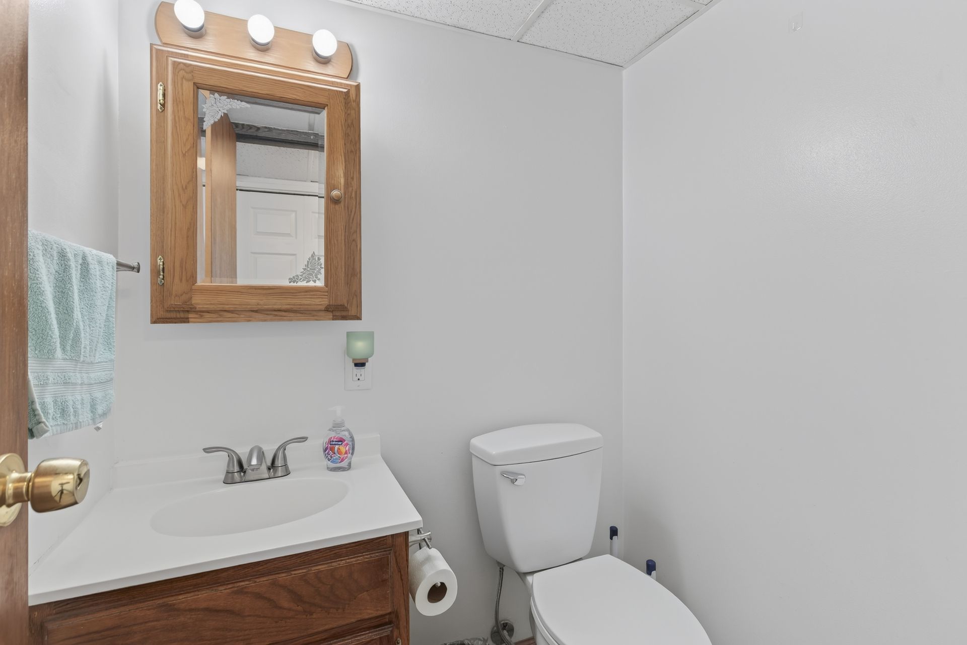 Small bathroom with white sink, mirror, toilet, and gray walls.