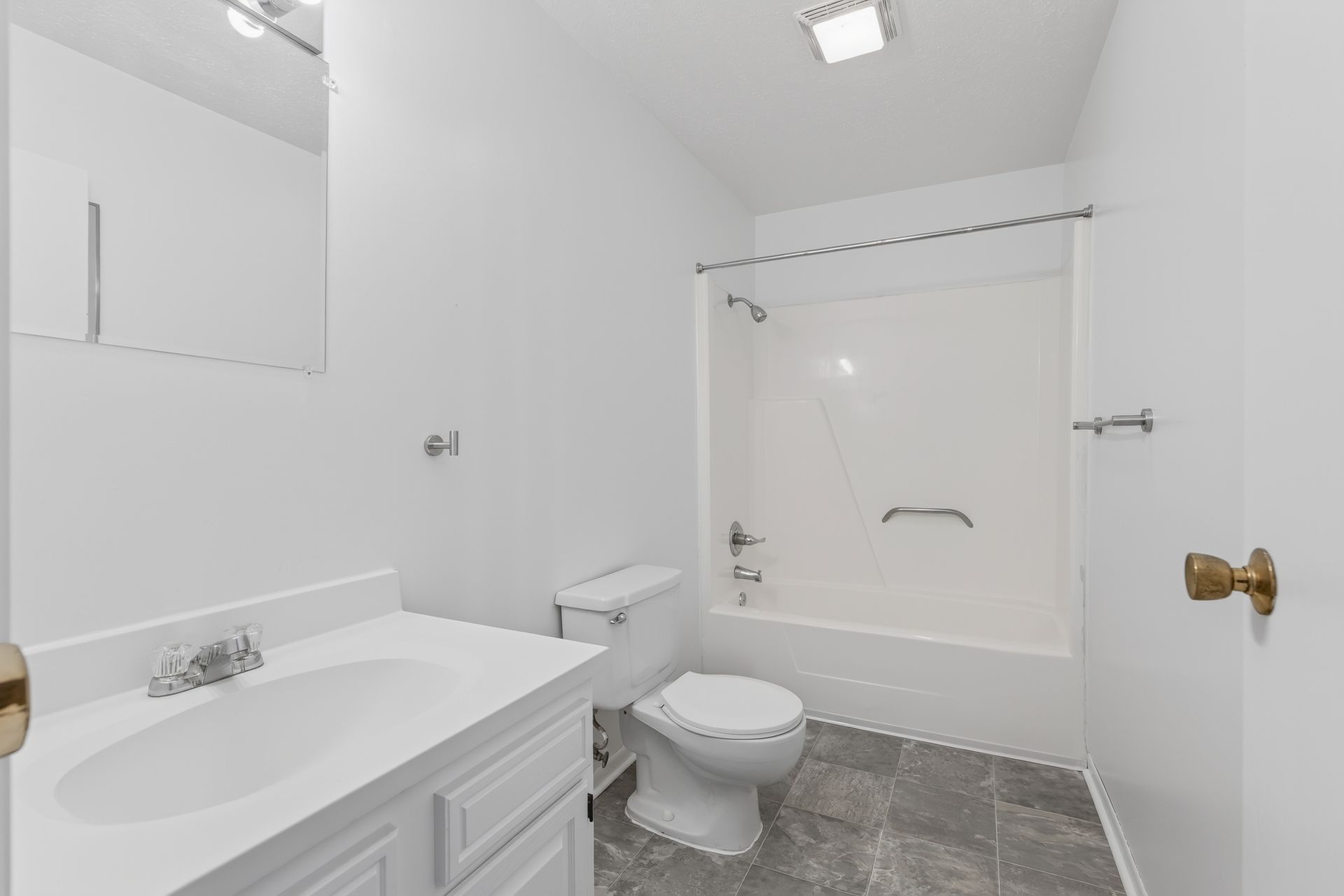 Bright white bathroom with vanity sink, toilet, and shower/tub combo with curtain.
