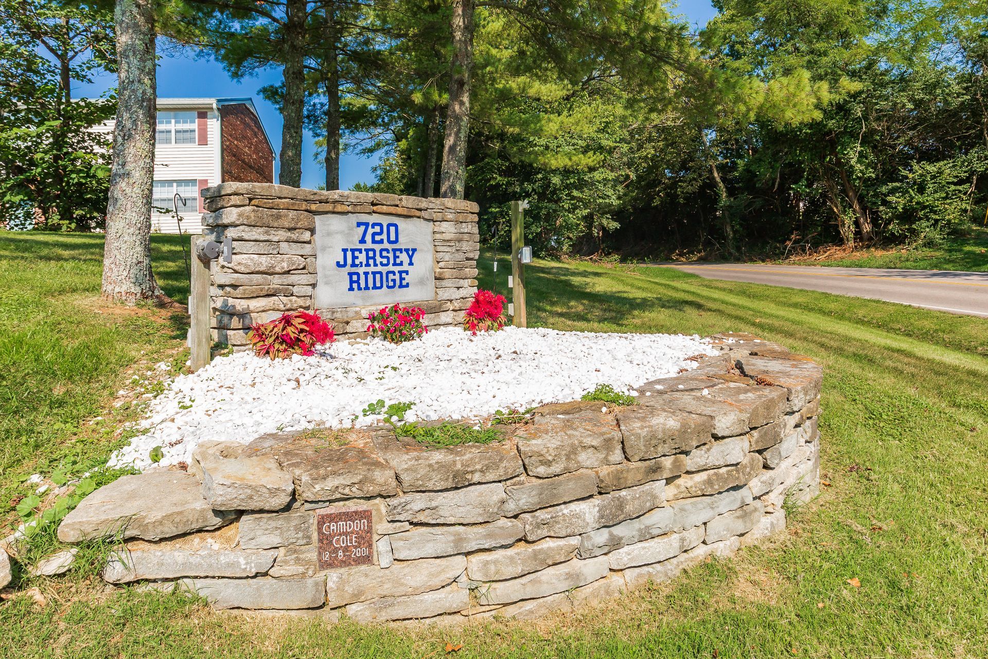 Stone roadside monument with sign reading “720 Jersey Joe” beside a tree-lined road