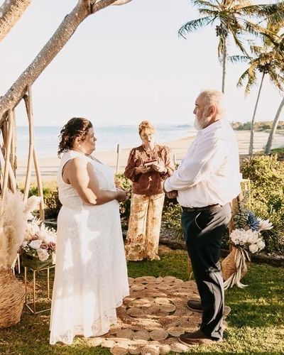A bride and groom are holding hands during their wedding ceremony.