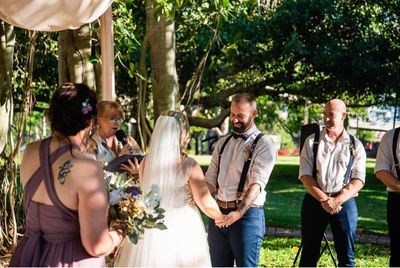 A bride and groom are holding hands during their wedding ceremony.