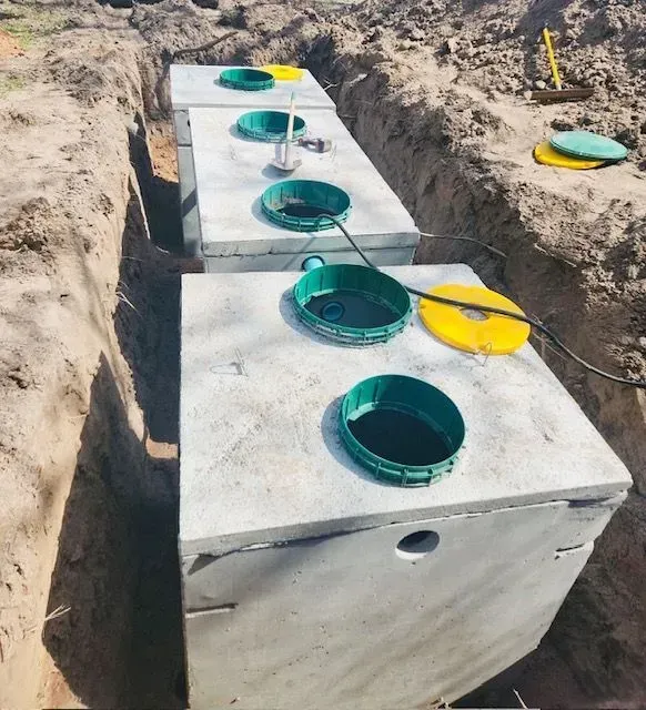 A row of septic tanks in a trench with green lids