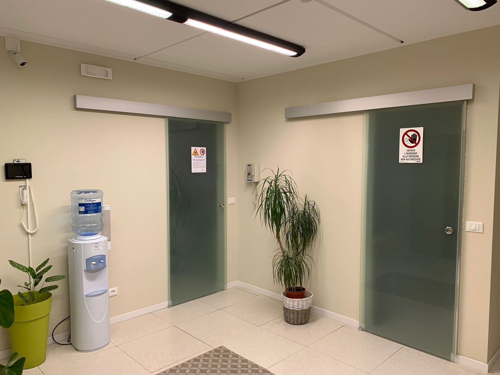 Una stanza con porte scorrevoli in vetro e un distributore d'acqua del centro medico e dentistico itaca bollate