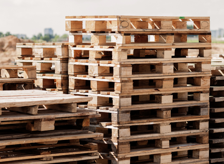 A pile of wooden pallets are stacked on top of each other.