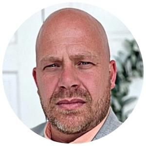 A bald man with a beard is wearing a suit and tie.