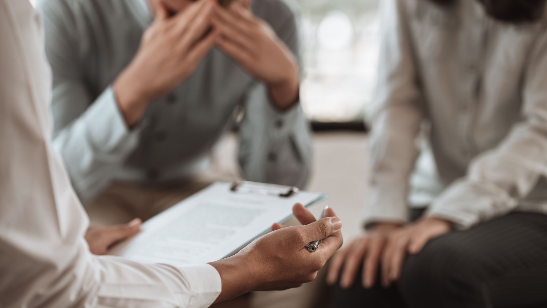 People in a meeting discussing documents at a table, with one person gesturing while others listen.