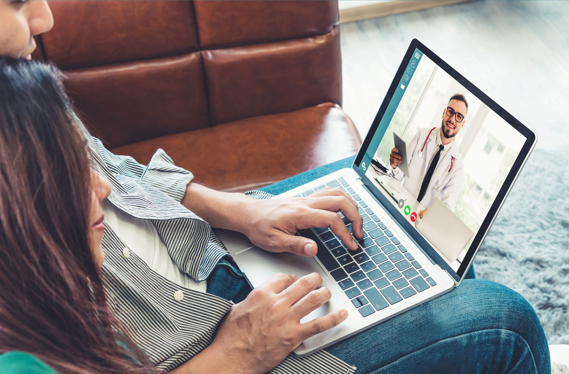 Person using a laptop for a video call while sitting on a couch