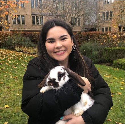 A woman is holding a brown and white rabbit in her arms.