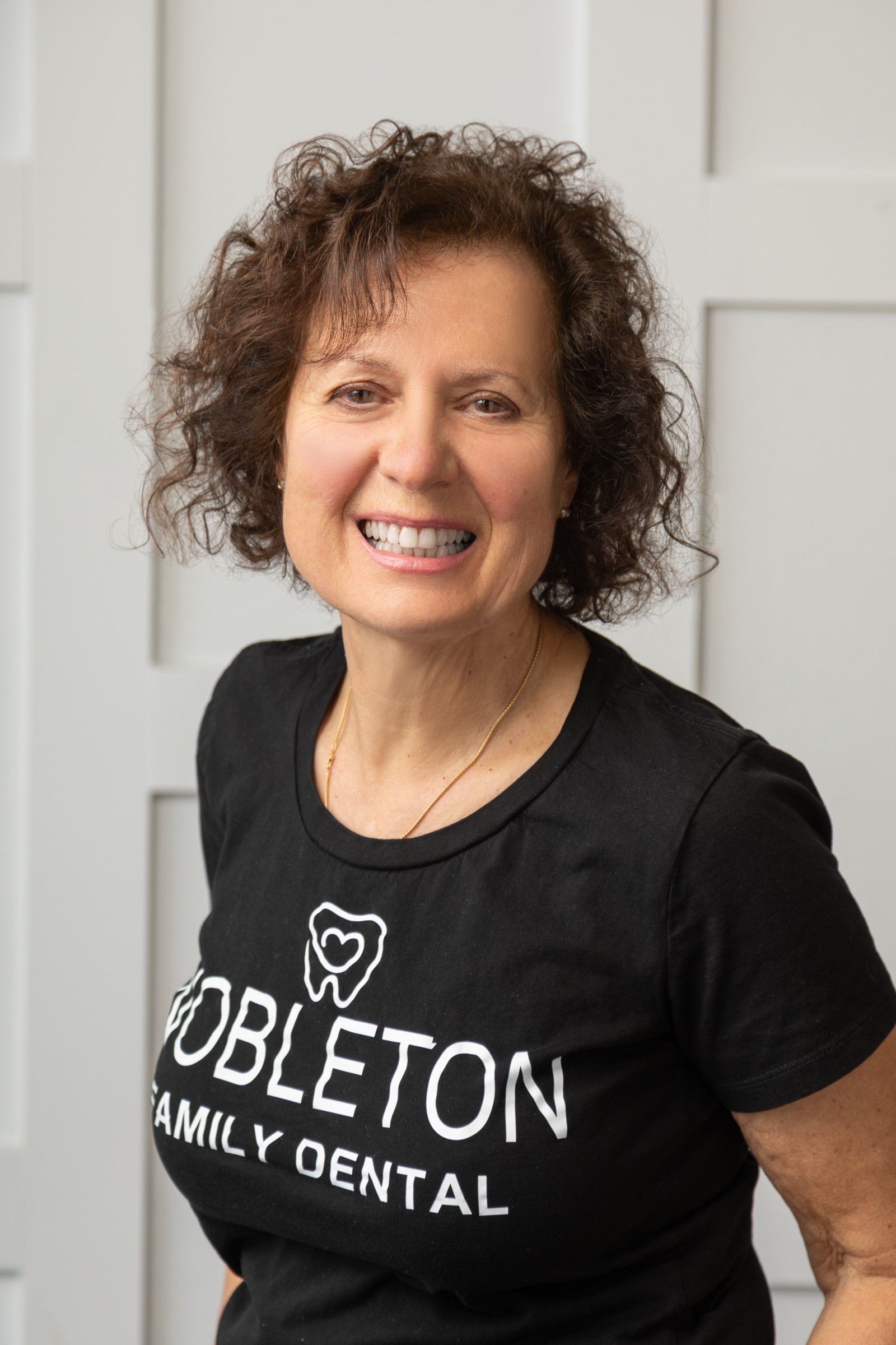 Woman with curly hair smiling, wearing black
