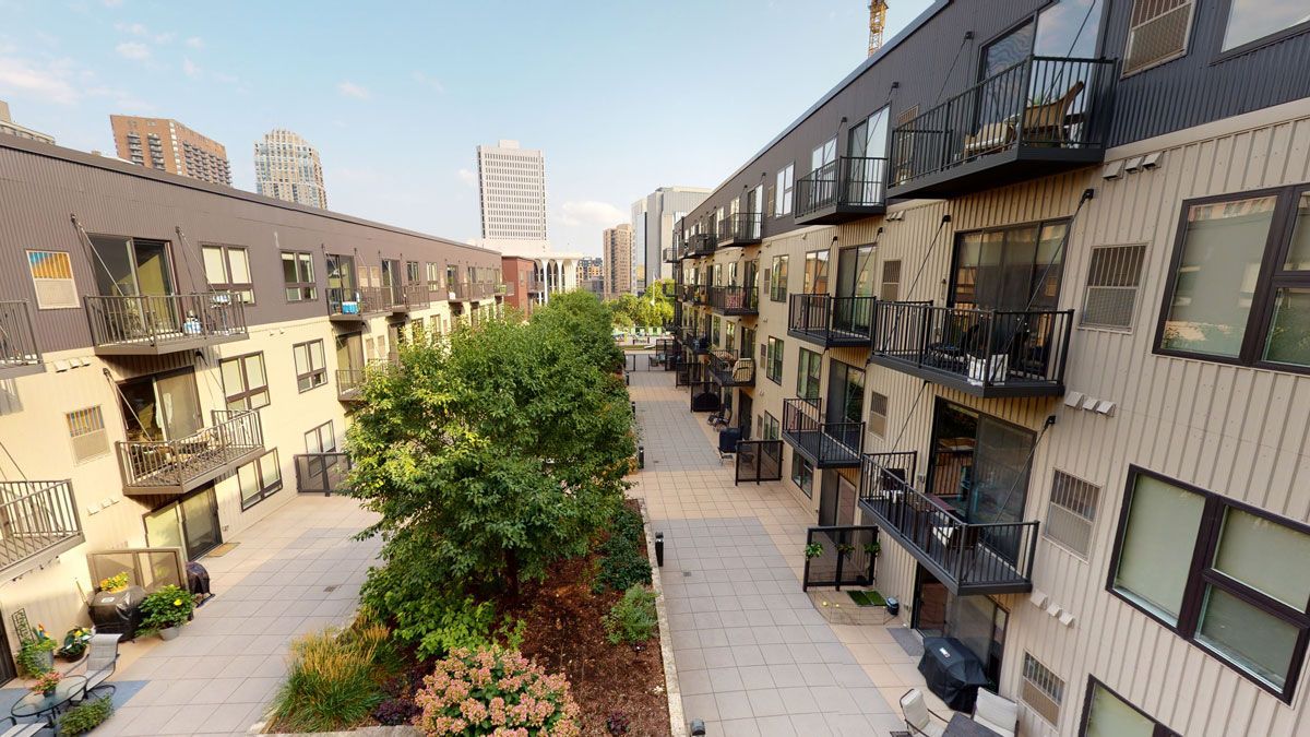 Courtyard view of apartment buildings with balconies and a tree-lined walkway