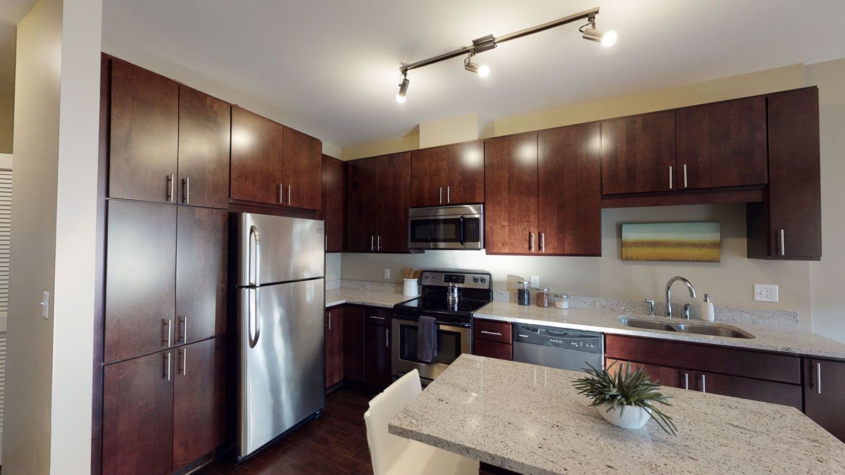Modern kitchen with dark wood cabinets, stainless steel appliances, and a granite island countertop.