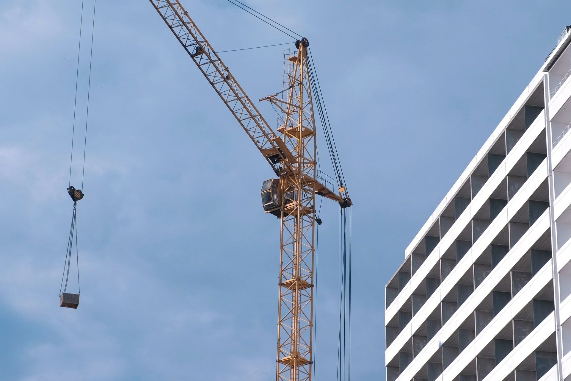 Construction crane beside a white building against a blue sky