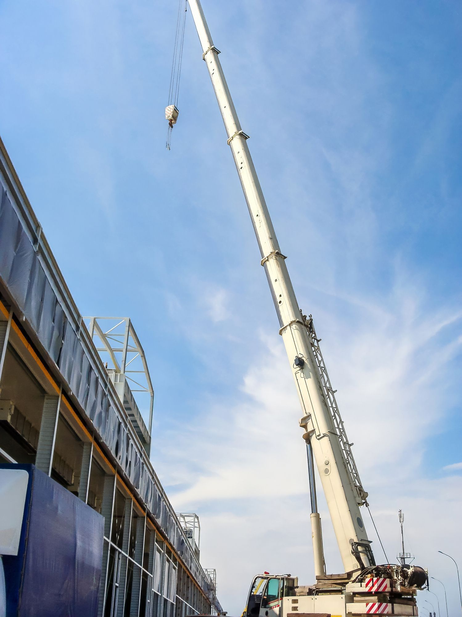 Crane lifting materials beside a construction site against a blue sky