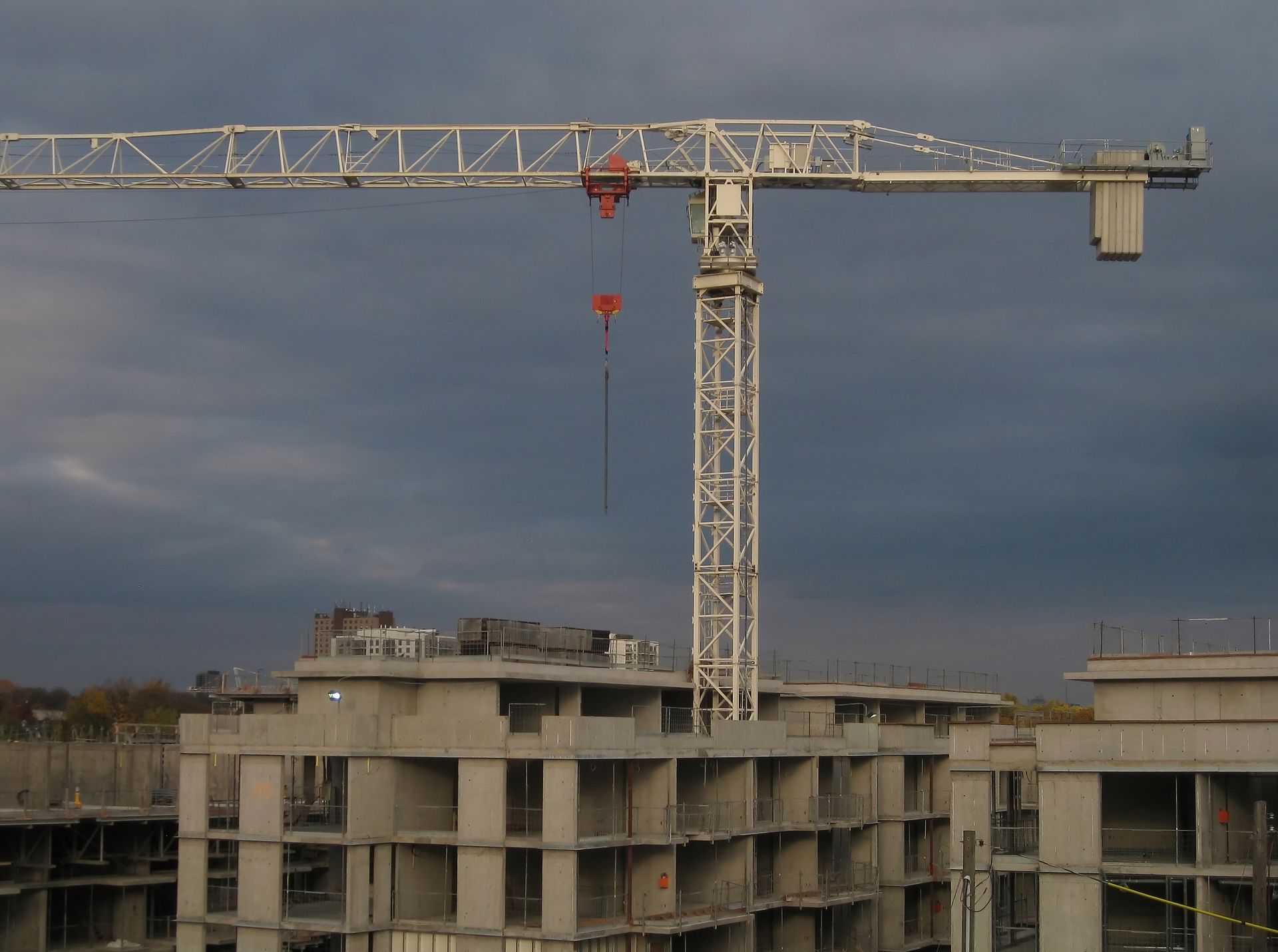 Construction crane over unfinished apartment building under cloudy sky