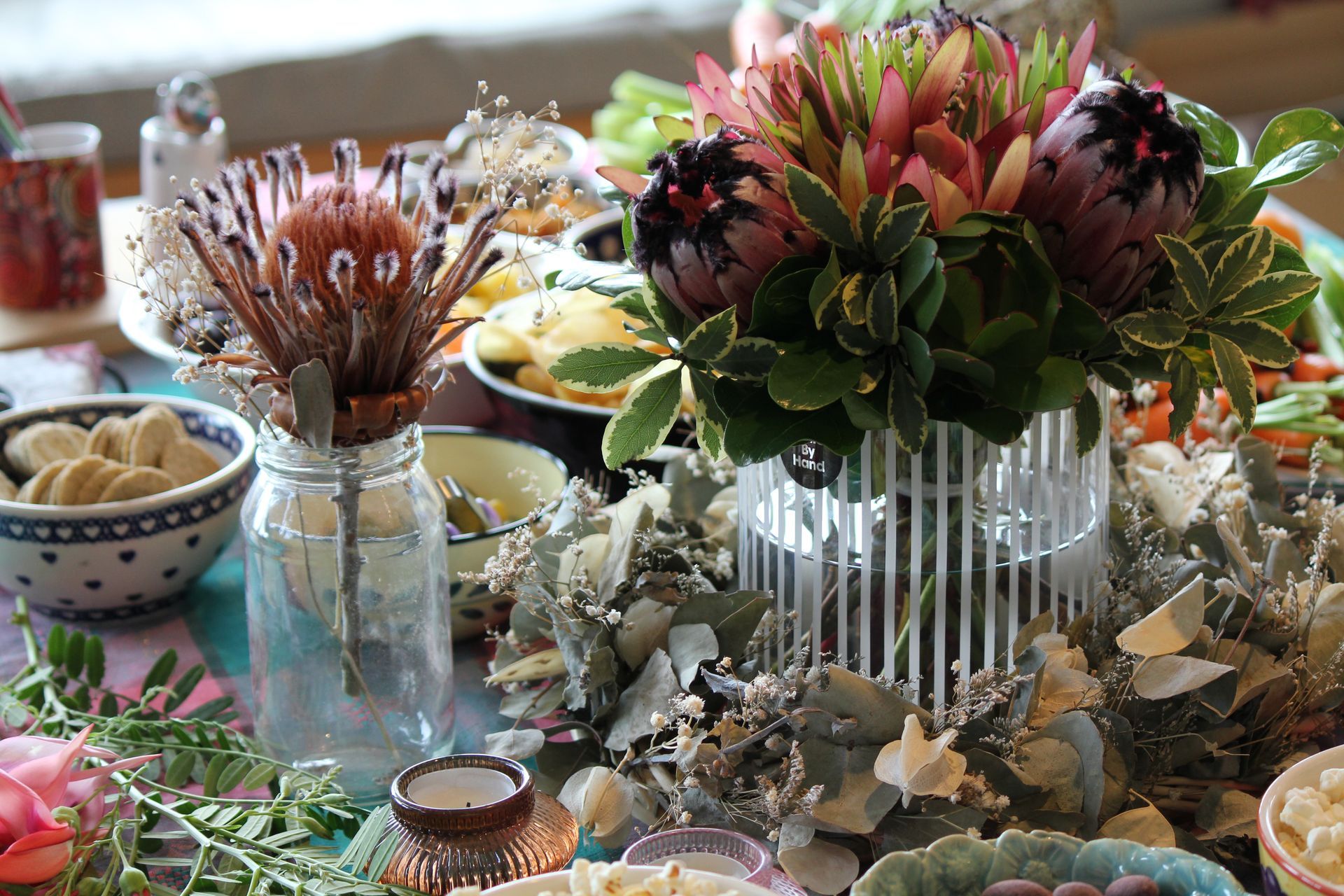 A table topped with a vase of flowers and bowls of food.