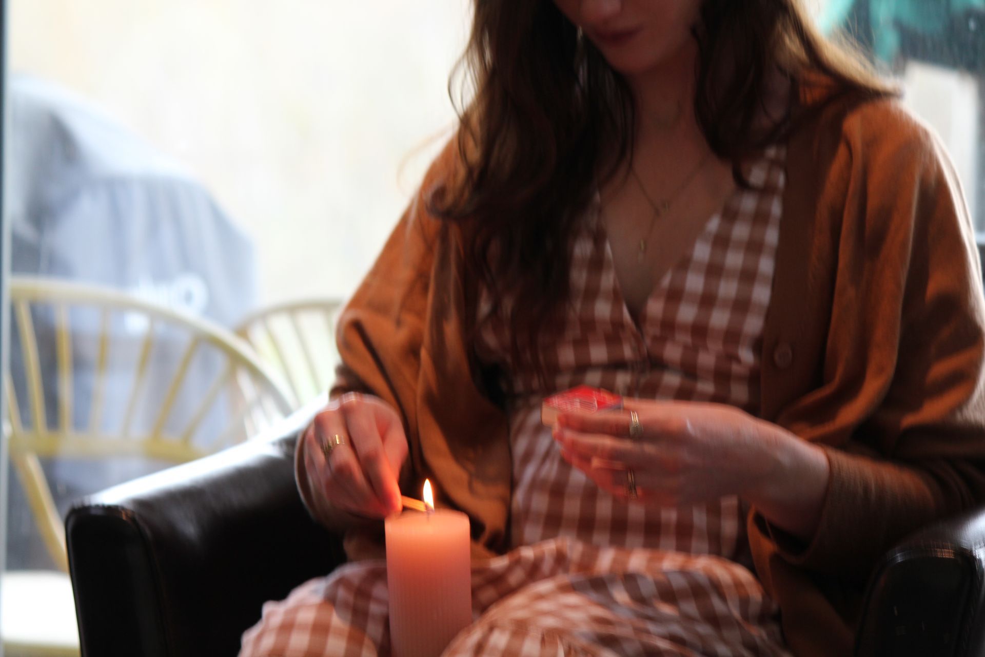 A woman is sitting in a chair lighting a candle.