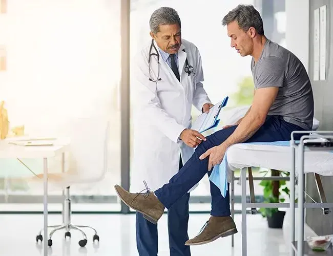 a doctor is examining a patient 's knee in a hospital .