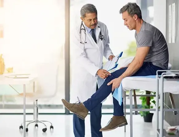 a doctor is examining a patient 's knee in a hospital .