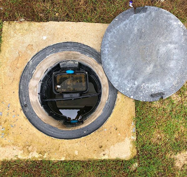 A Manhole Cover With the Lid Open and a Meter Inside of It — Elite Wastewater Solutions in Tallong, NSW