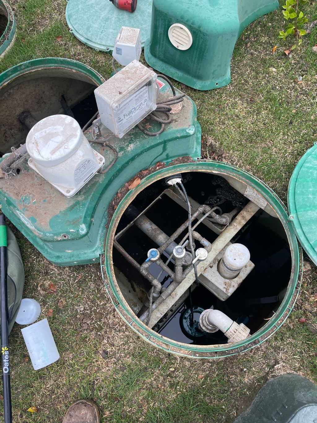 A Man is Pumping a Green Pipe Into a Manhole — Elite Wastewater Solutions in Mittagong, NSW