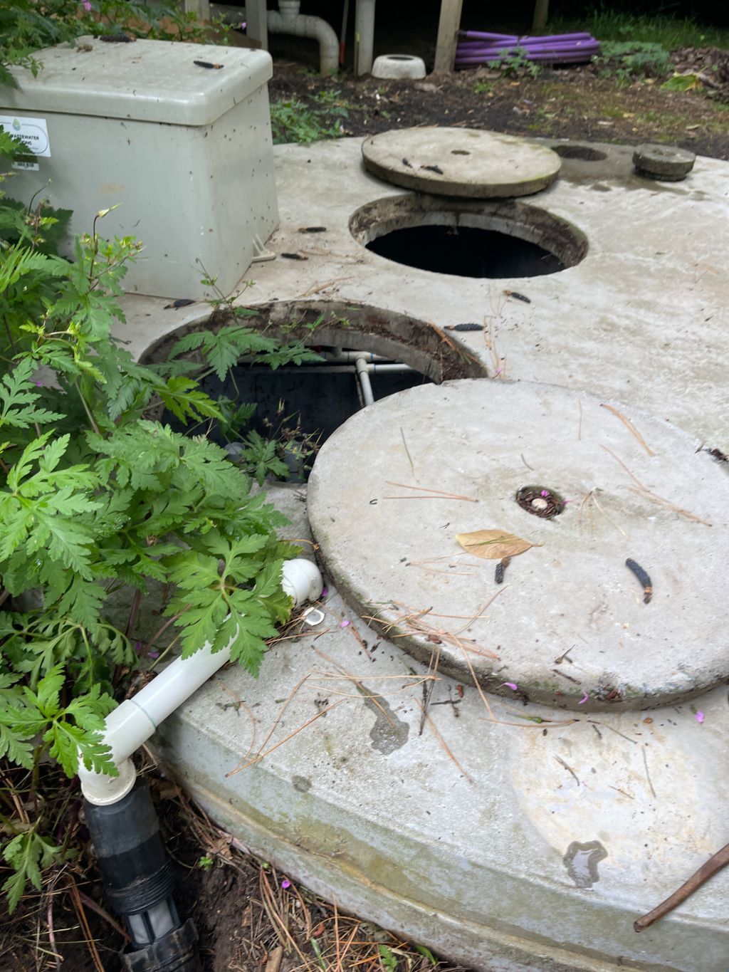 A Man is Pumping a Green Pipe Into a Manhole — Elite Wastewater Solutions in Wingello, NSW