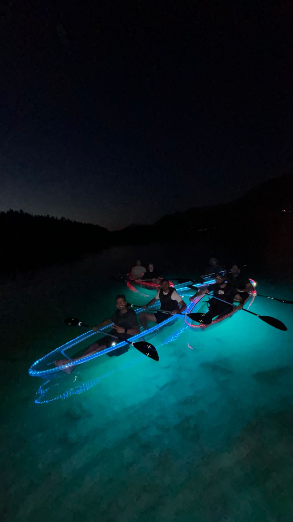A clear kayak glows turquoise against dark Montana water after sunset.