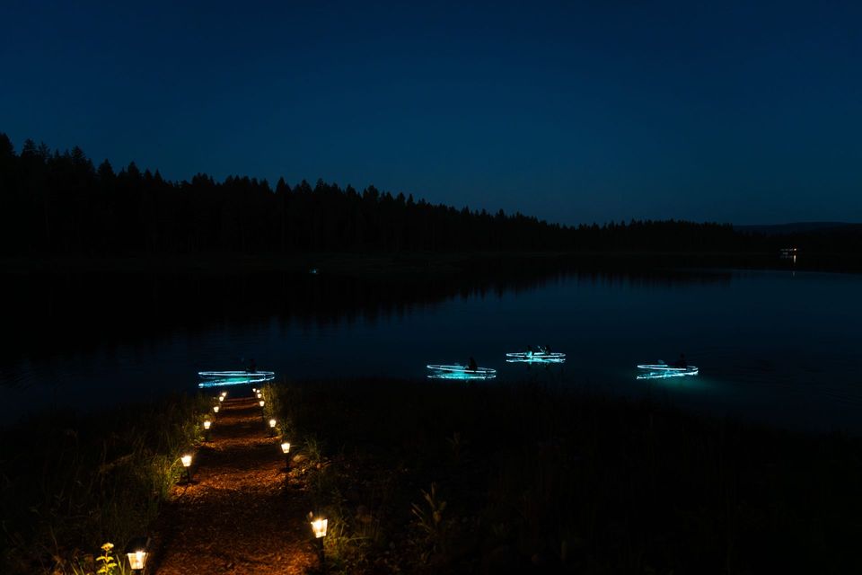 LED clear kayaks glow near the Montana lakeshore after dark.