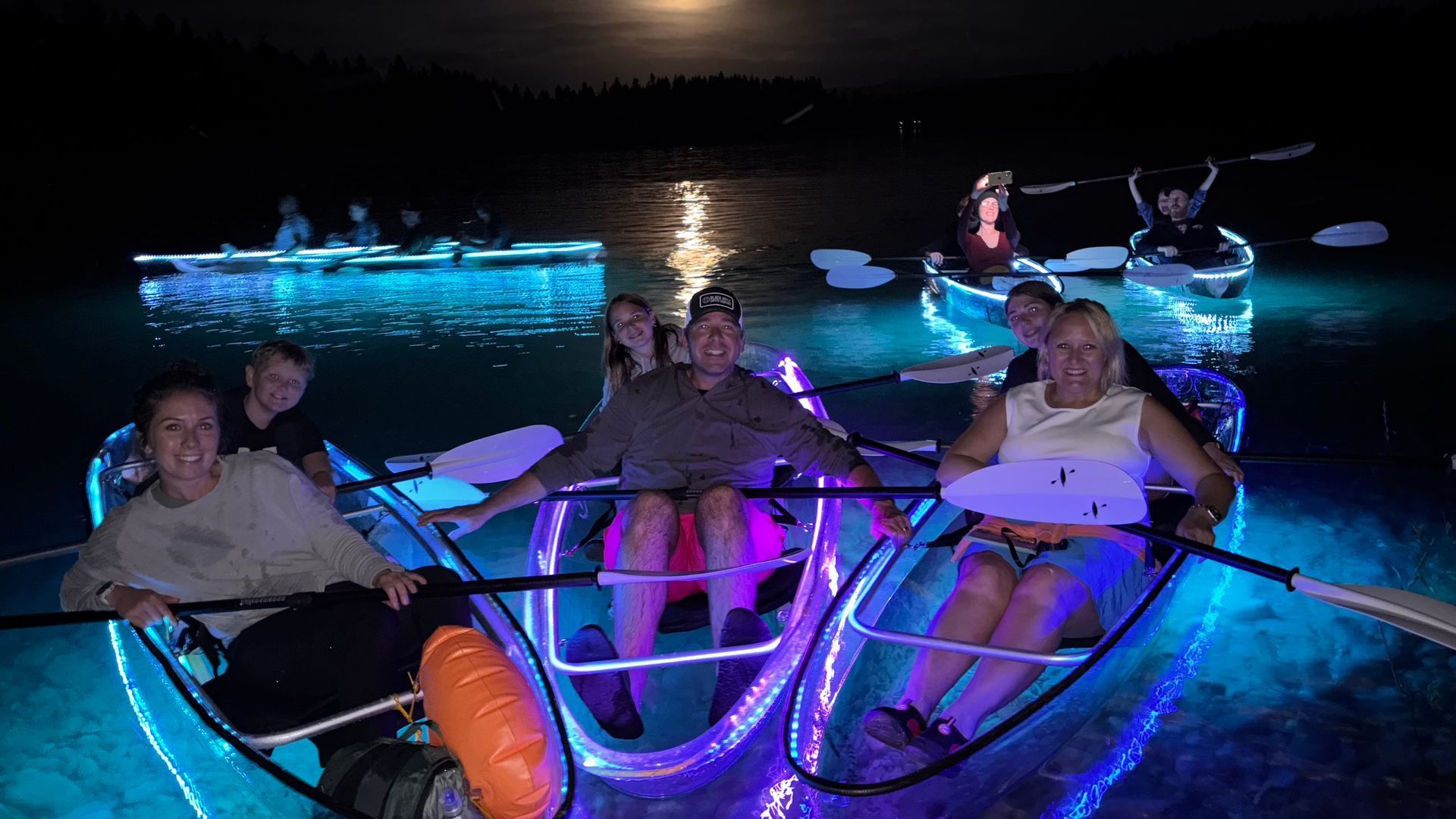 guided LED clear kayak sunset tour featuring transparent kayaks and scenic mountain views