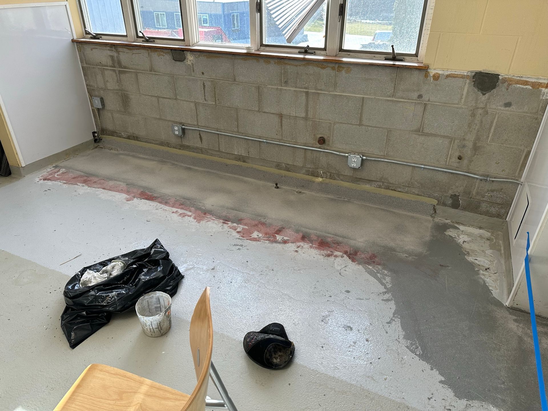 Partially renovated room with cinder block wall, exposed windows, and construction debris on the floor