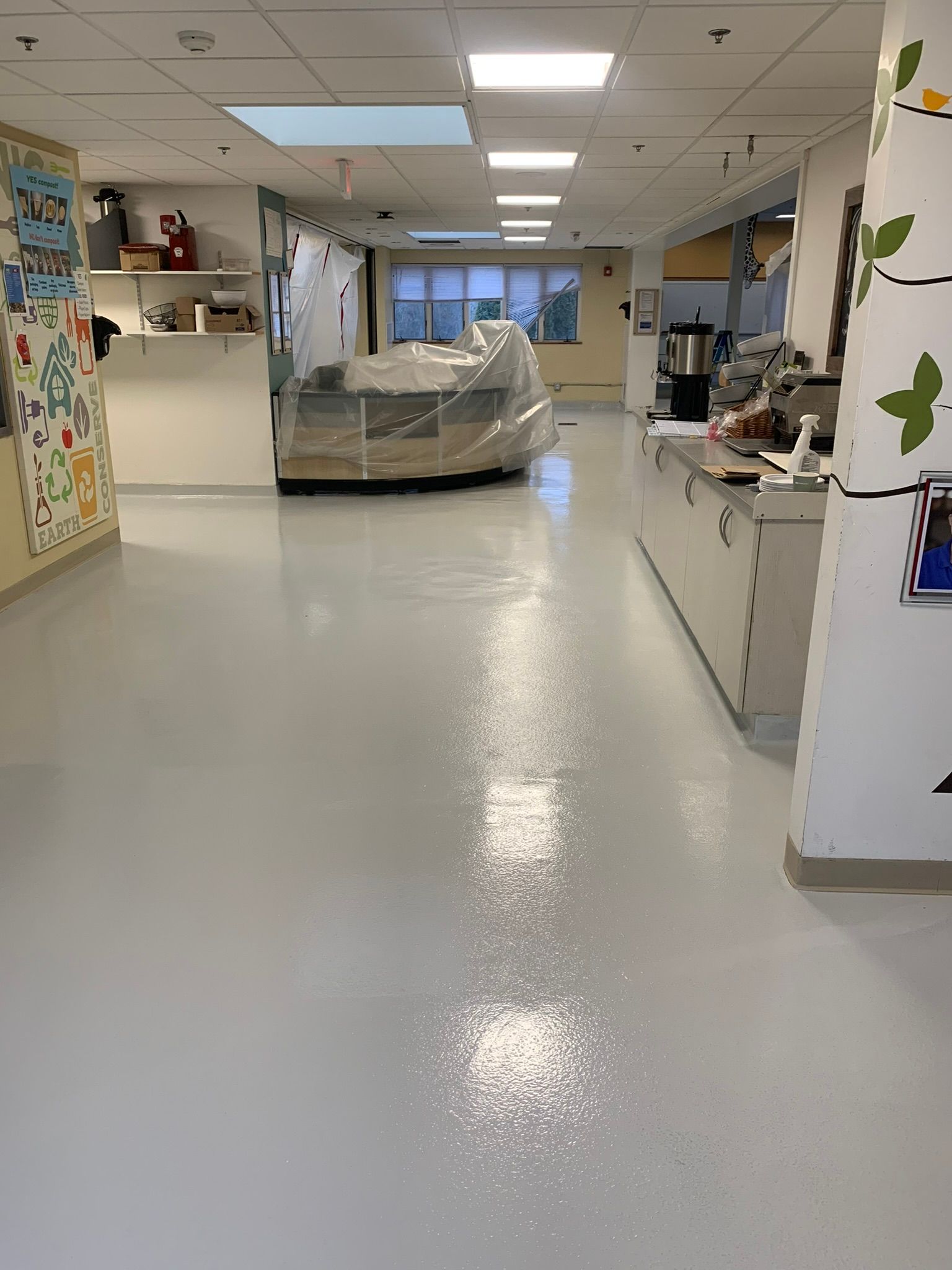 Hospital corridor with a covered medical cart under bright ceiling lights.