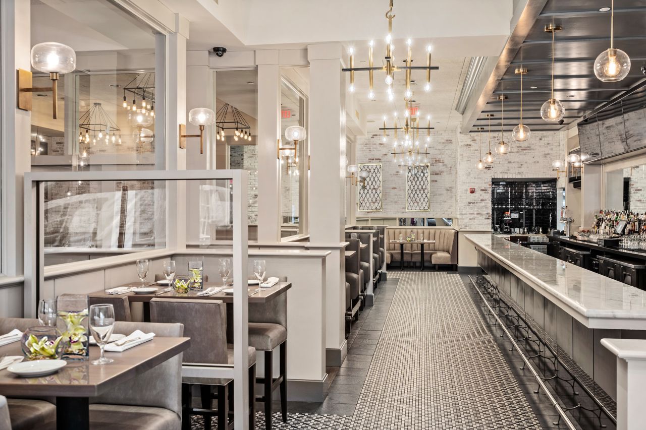 Elegant restaurant interior with patterned tile floor, white booths, and chrome accents