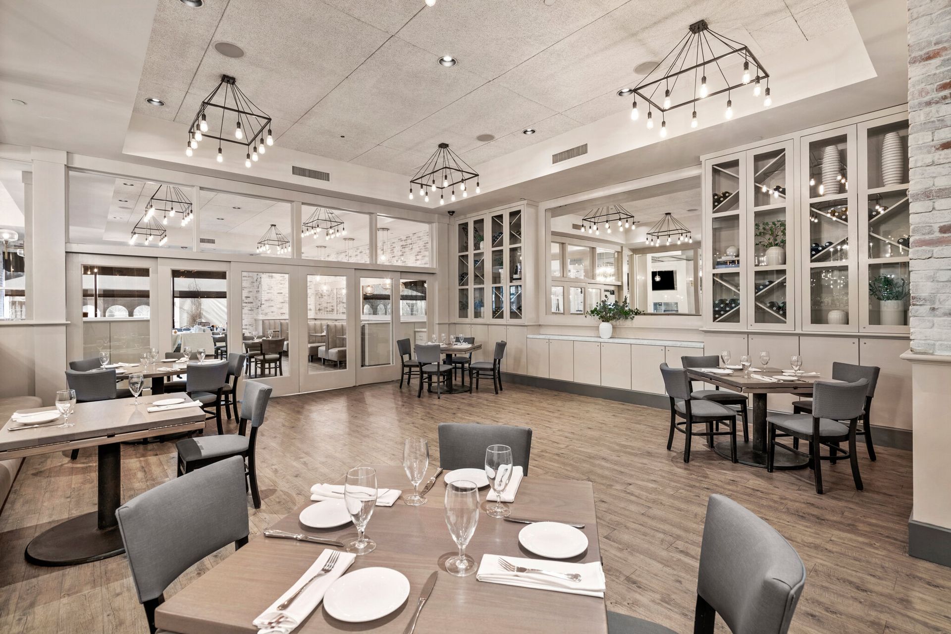 Bright restaurant dining room with tables set with plates and chairs under pendant lights