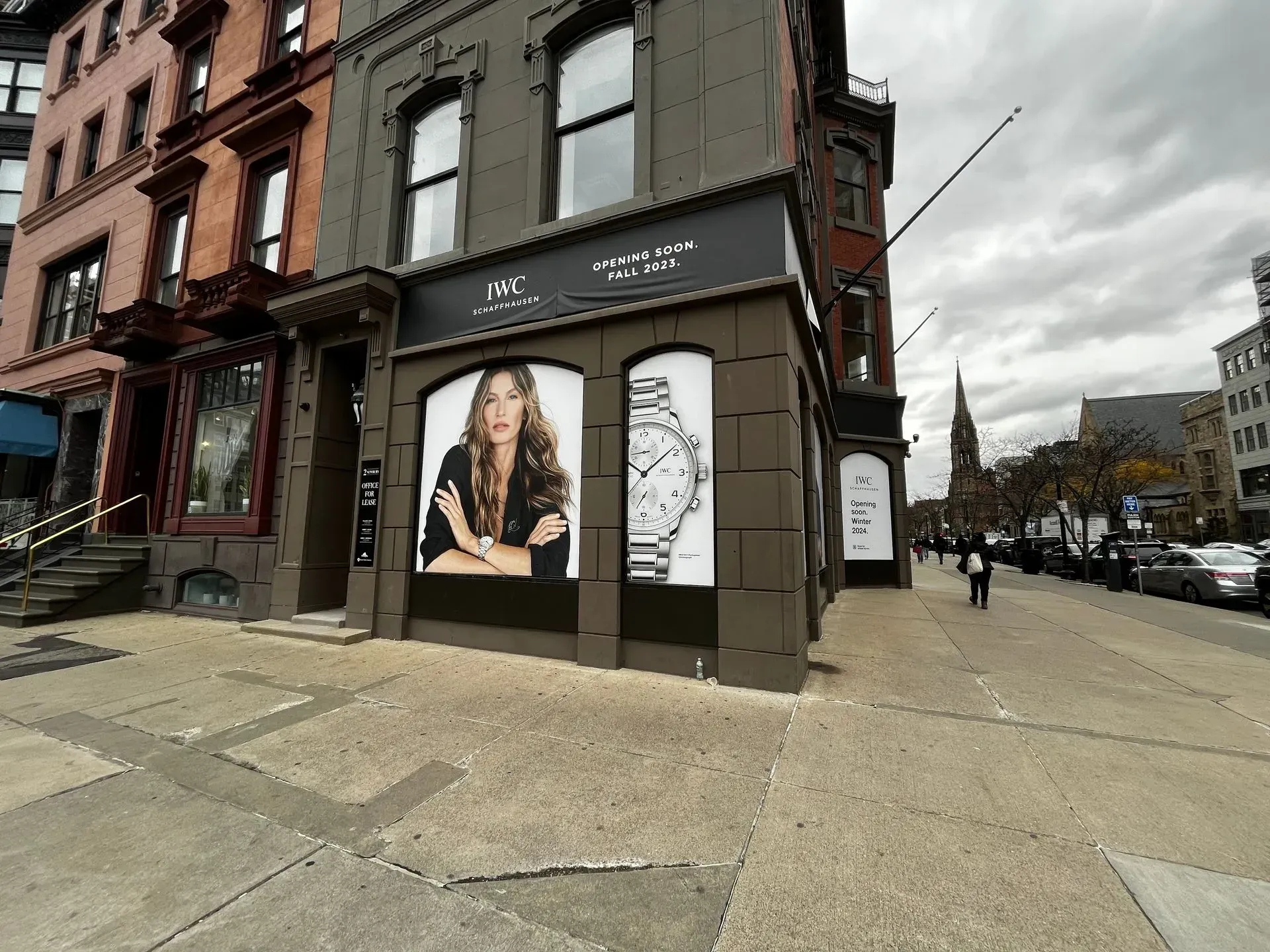 Street corner storefront with fashion posters on a brick building under a cloudy sky