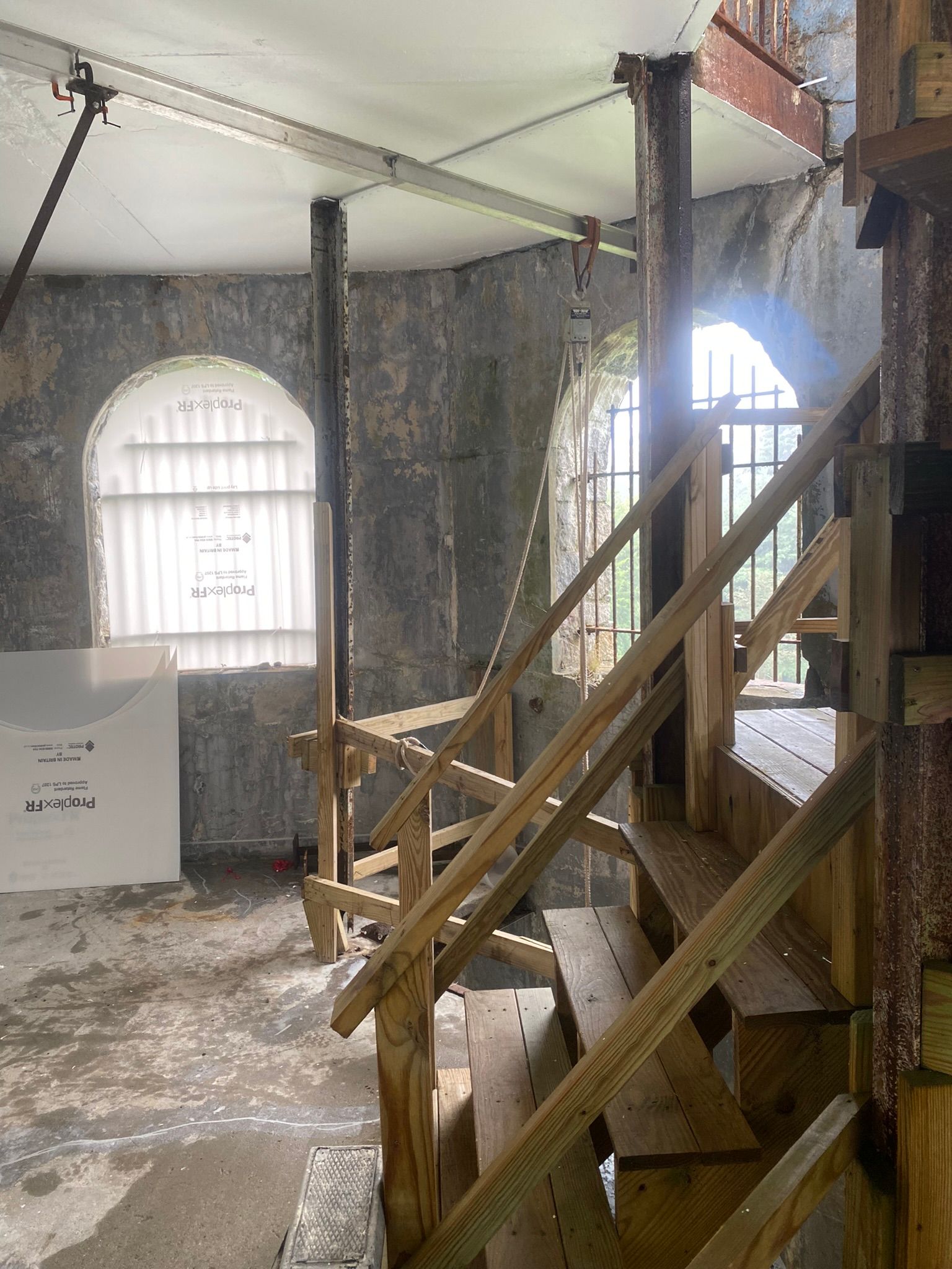 Old industrial stairway inside a brick room with arched windows and exposed beams