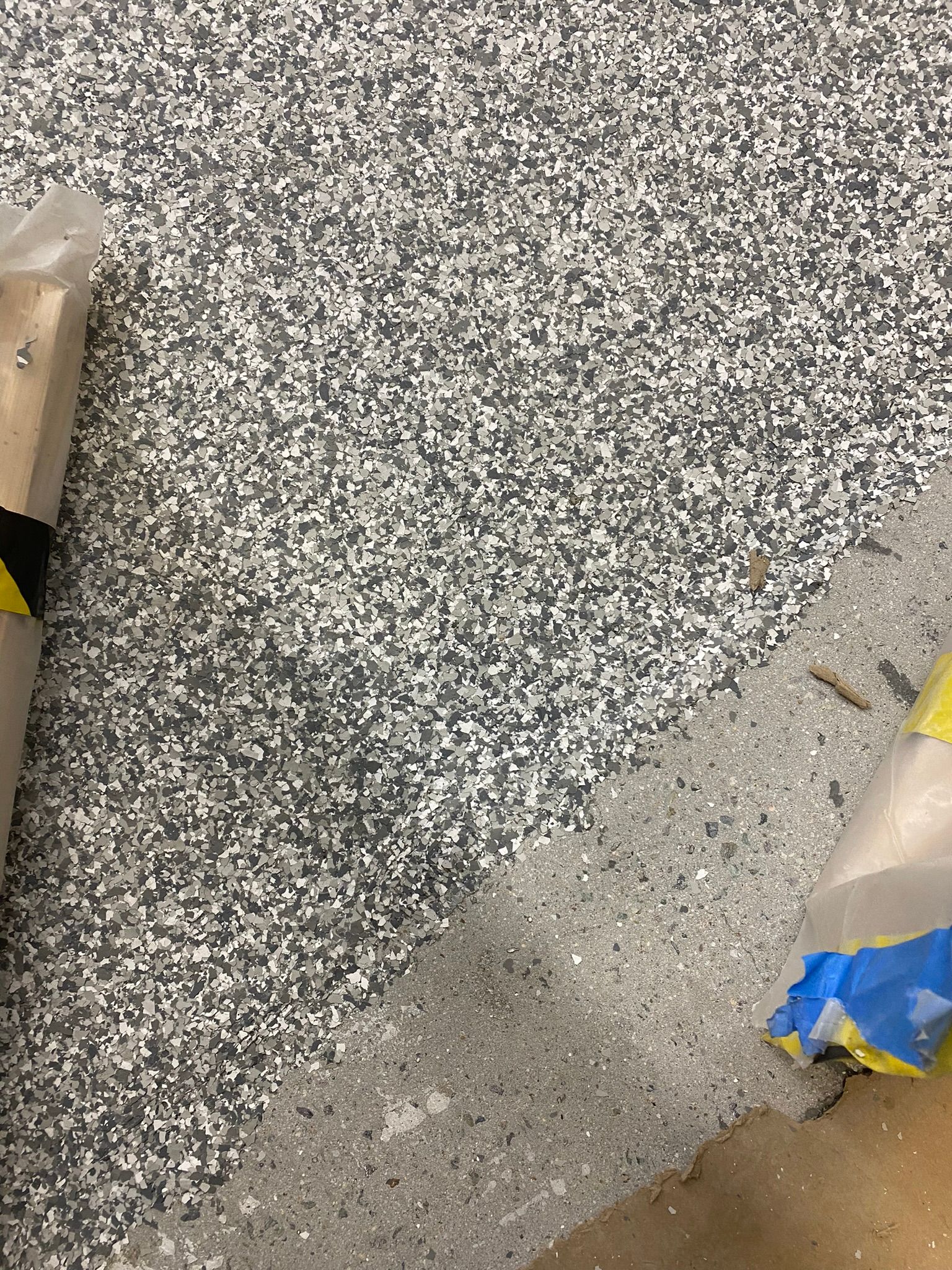 Speckled gray flooring with a diagonal strip of lighter concrete and taped-off edges.