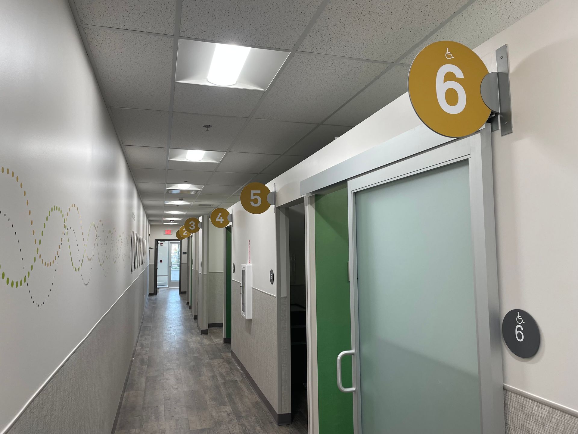 Modern hallway with frosted glass doors and numbered room signs 5 and 6 on the right.