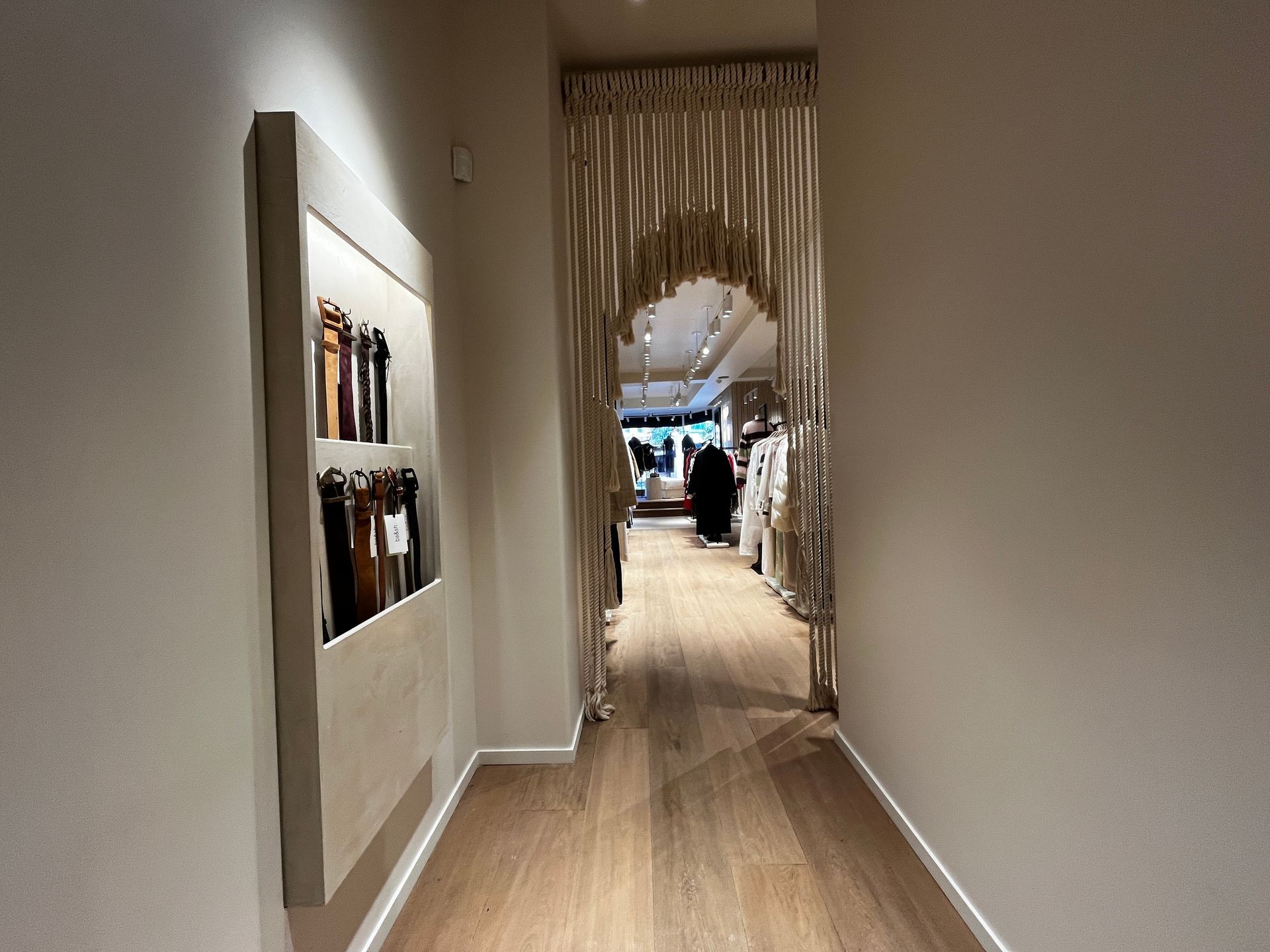 Long hallway with wood flooring, white walls, and a decorative archway at the end