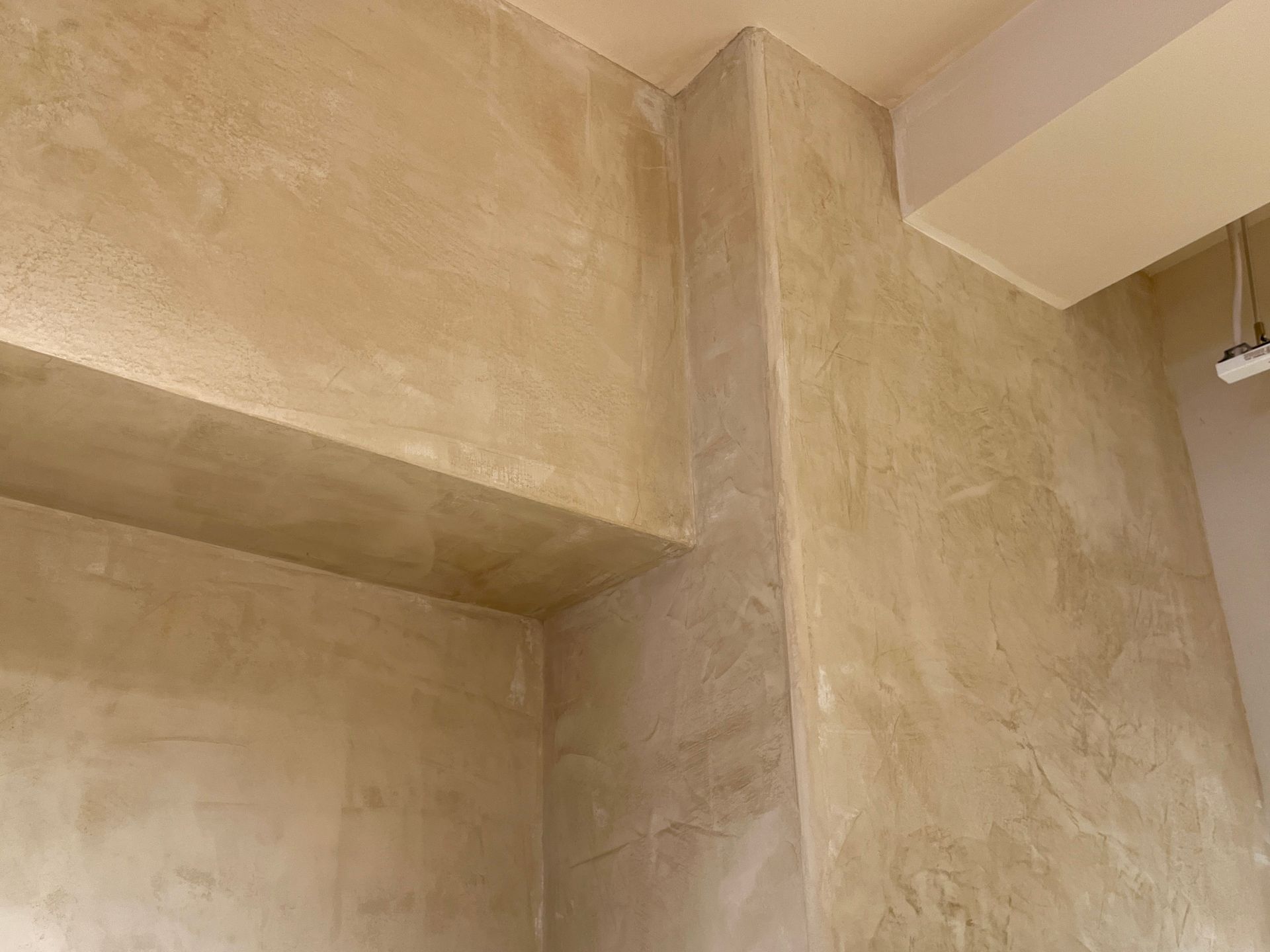 Beige textured interior wall and ceiling corner with a beam overhead