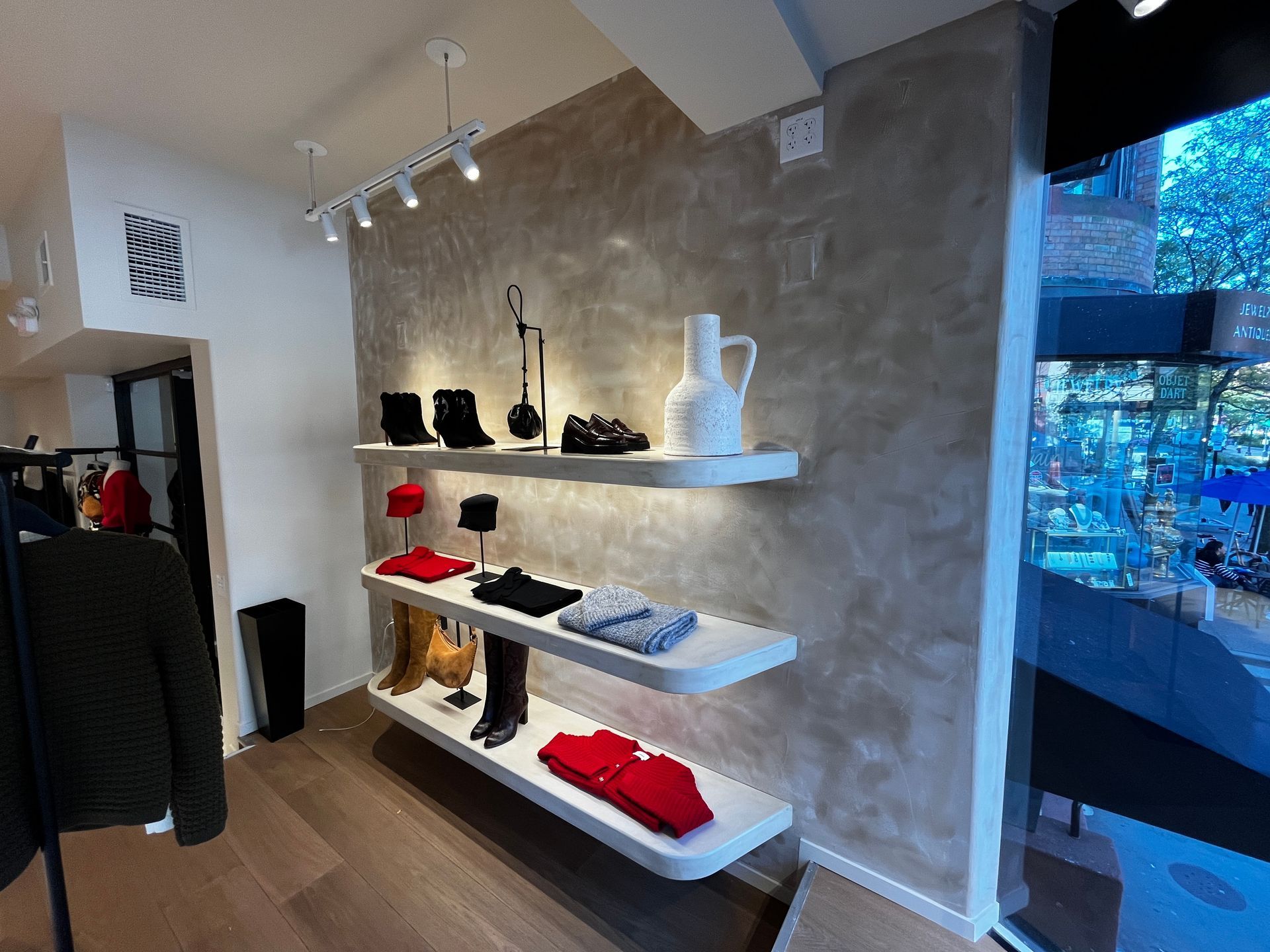 Boutique store display with white shelves, black decor, and red folded items on a textured wall