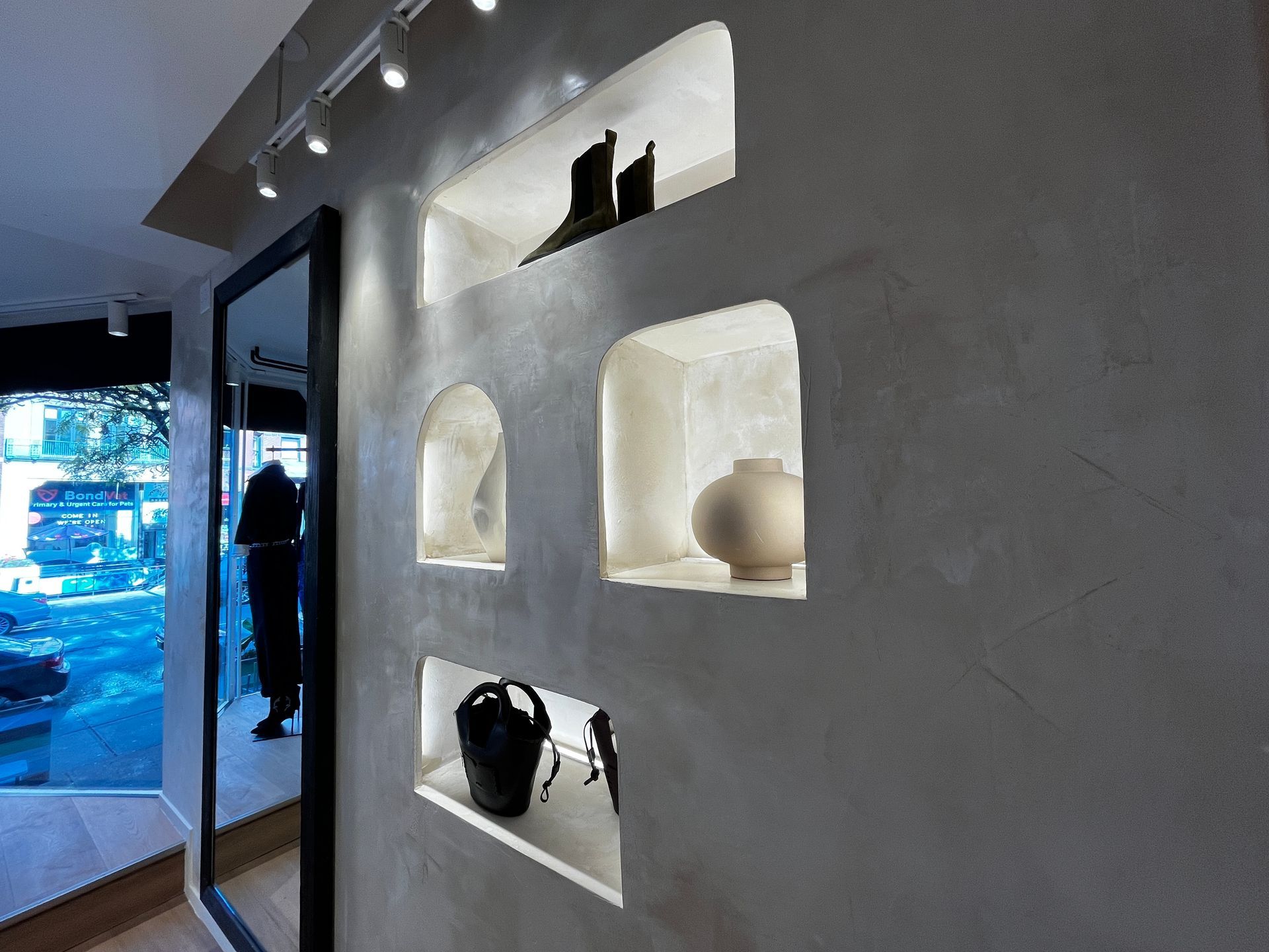 Modern gray wall with built-in display niches holding pottery and decor, near a glass doorway
